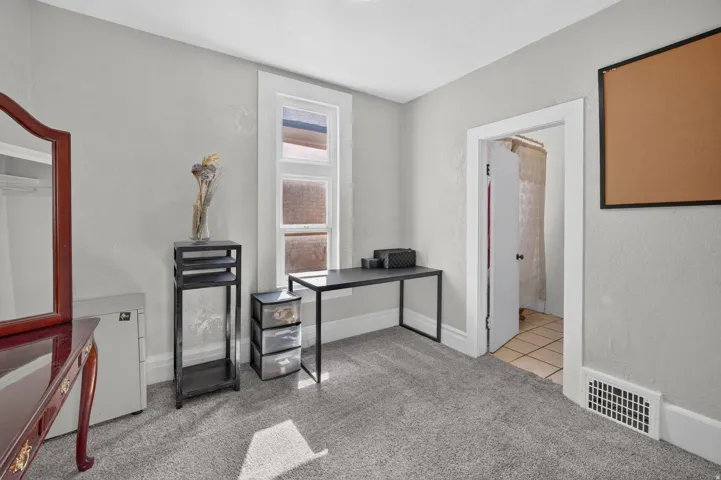 Light grey wall finish with white trim, grey carpet flooring, and a single window with white framing