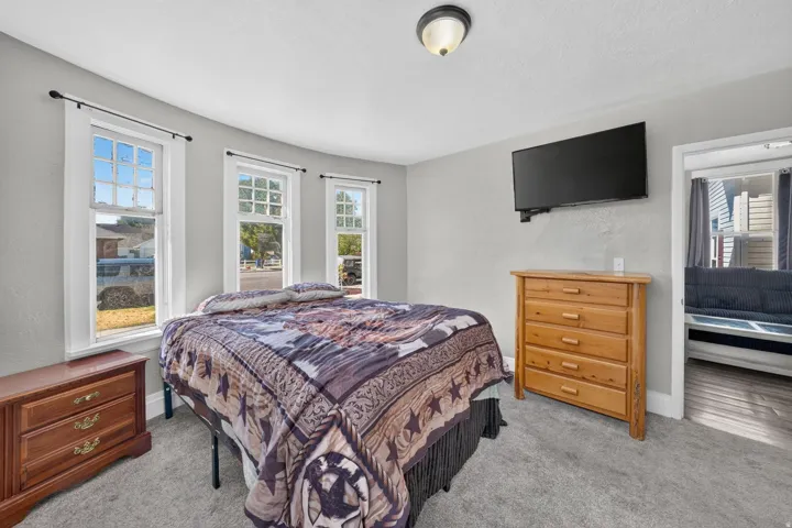 Light gray walls, three paneled windows, gray carpet, and a ceiling-mounted light fixture