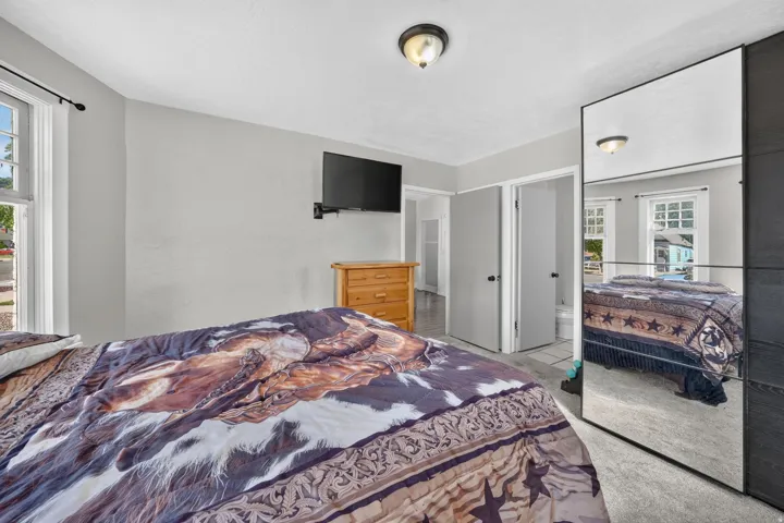 Recessed lighting, window with sash, ceiling-mounted light fixture, light gray wall paint, and mirrored wardrobe doors