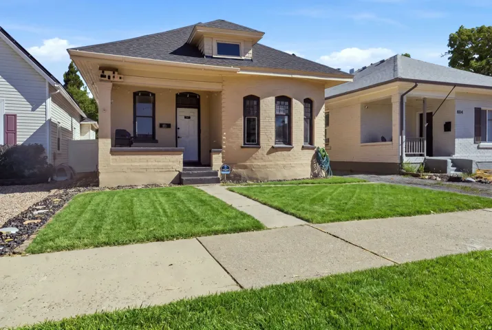 Traditional architecture featuring a covered porch, dormer window, and dark-framed windows