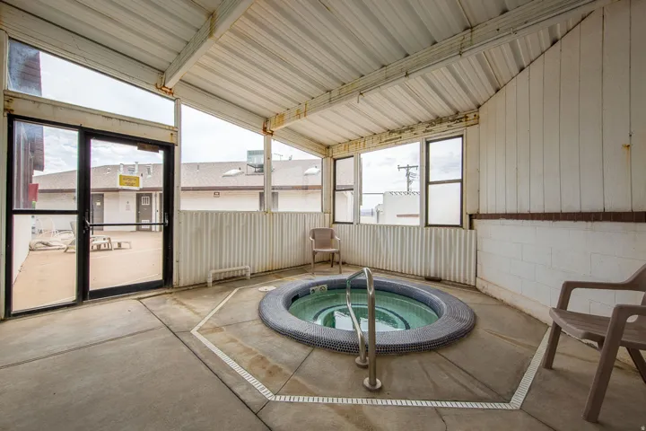 Indoor spa with mosaic tile surround, integrated grab rail, and concrete flooring