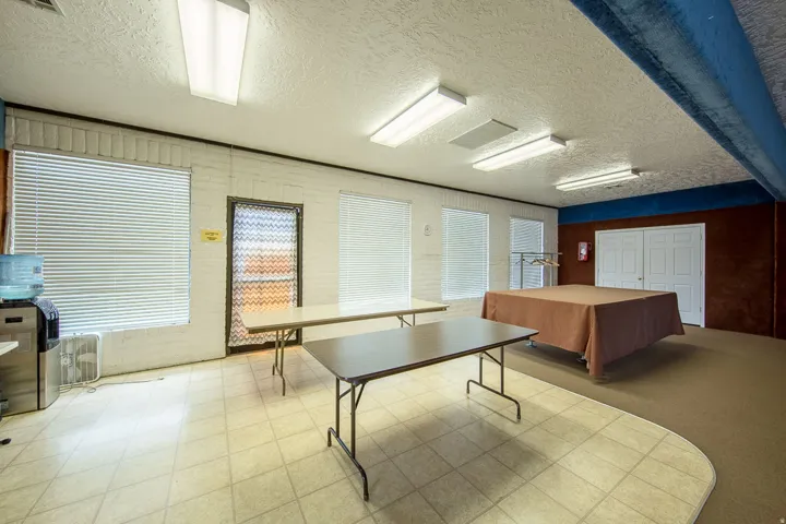 Spacious room featuring multiple windows with blinds, a tiled floor area, and a carpeted section