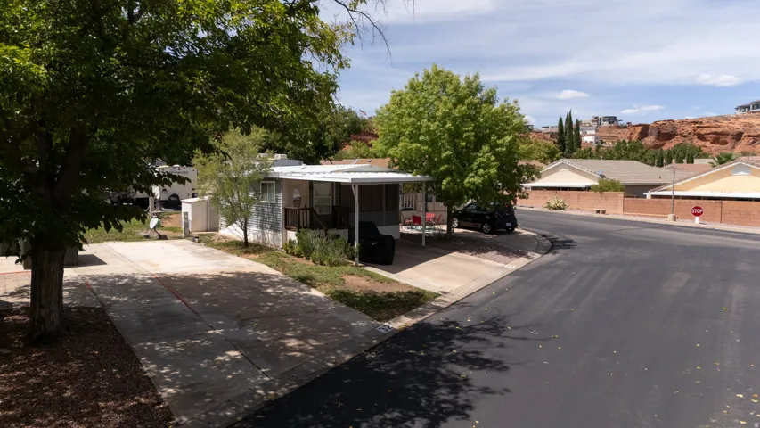 Manufactured home with an attached screened porch, covered parking, and an extended driveway