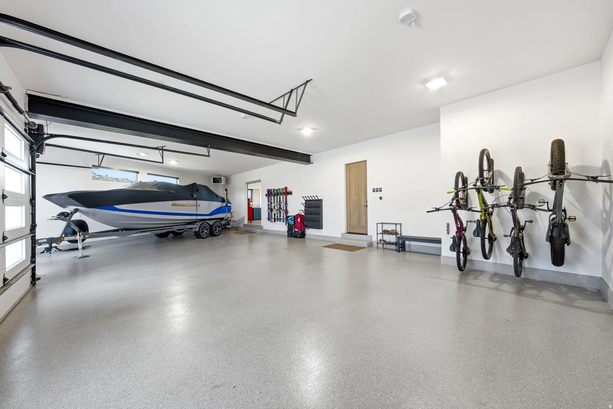 Expansive garage featuring an epoxy-coated concrete floor, bright overhead lighting, and white walls