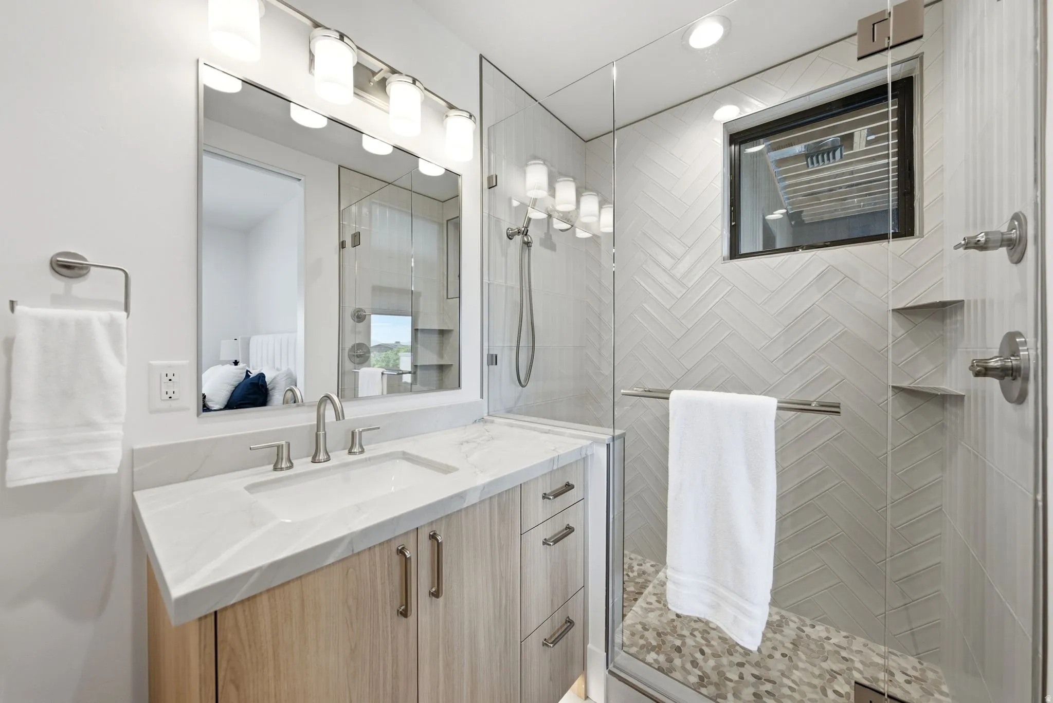 Spacious shower with glass enclosure and herringbone tile