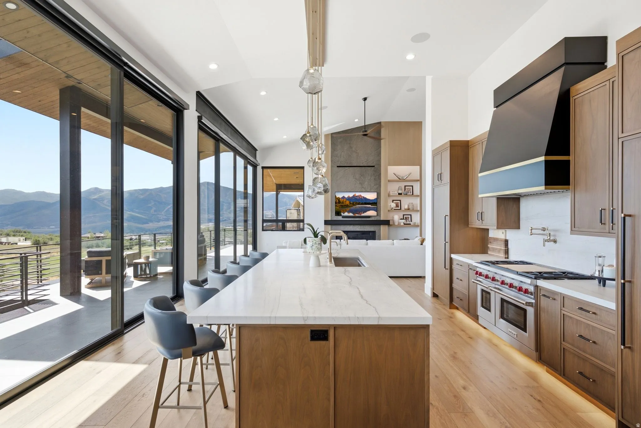 Open-concept kitchen featuring a large central island with seating, stainless steel appliances, and wood-finish cabinetry