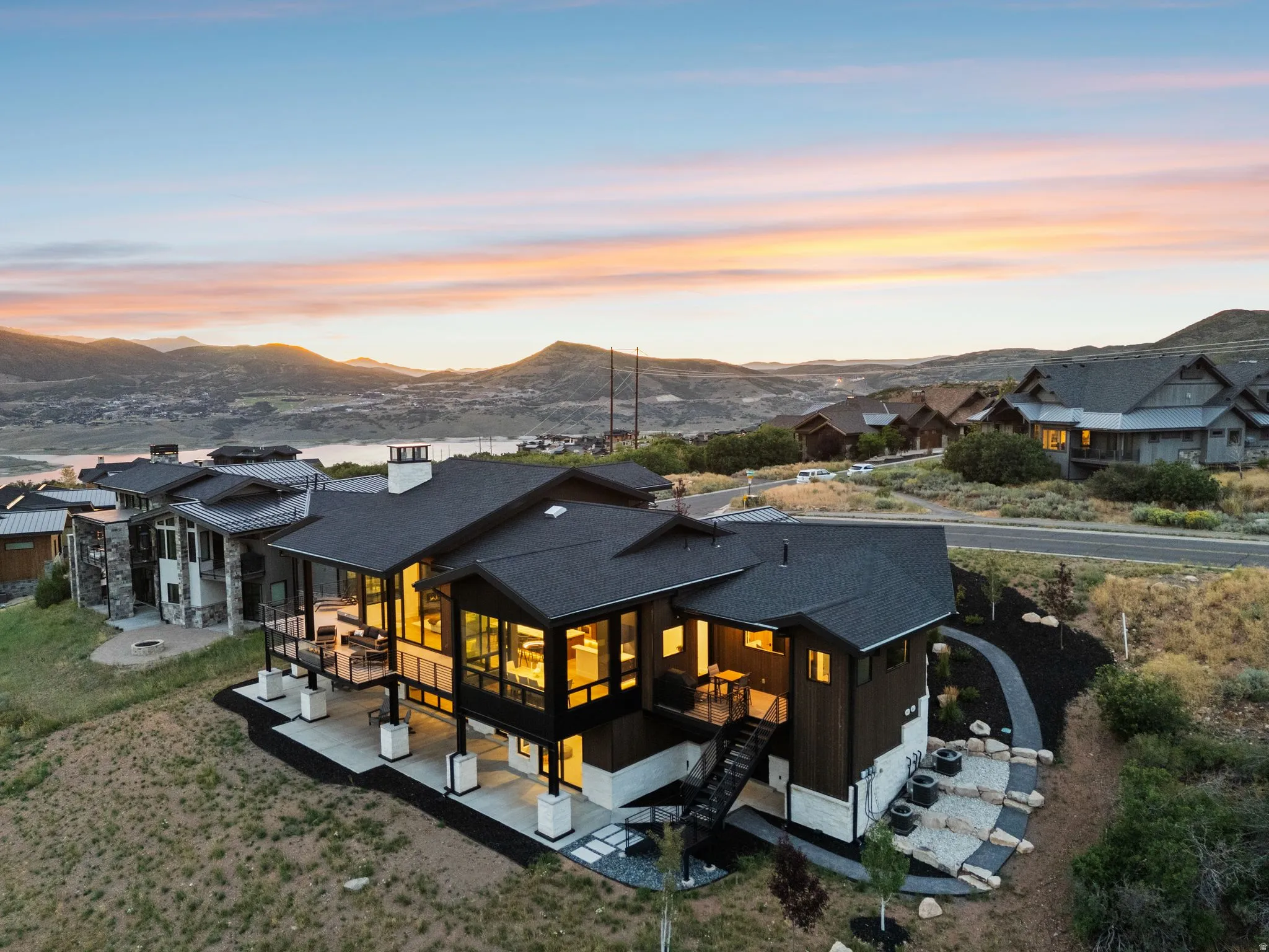 Modern architectural design with extensive window walls, multiple outdoor patio spaces, and a tiered exterior landscaping