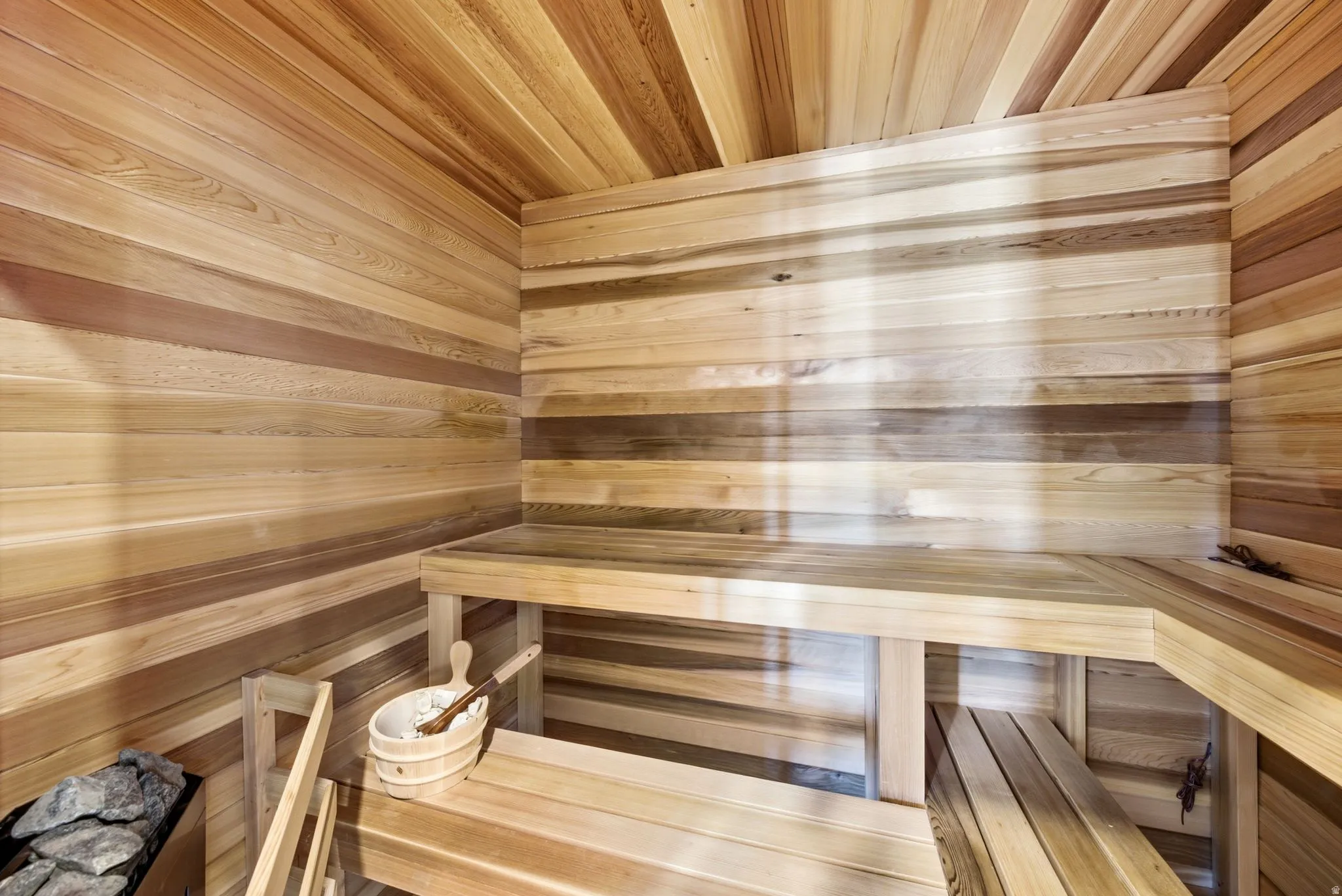 Wood-paneled interior with built-in wooden benches and a stone-filled heater