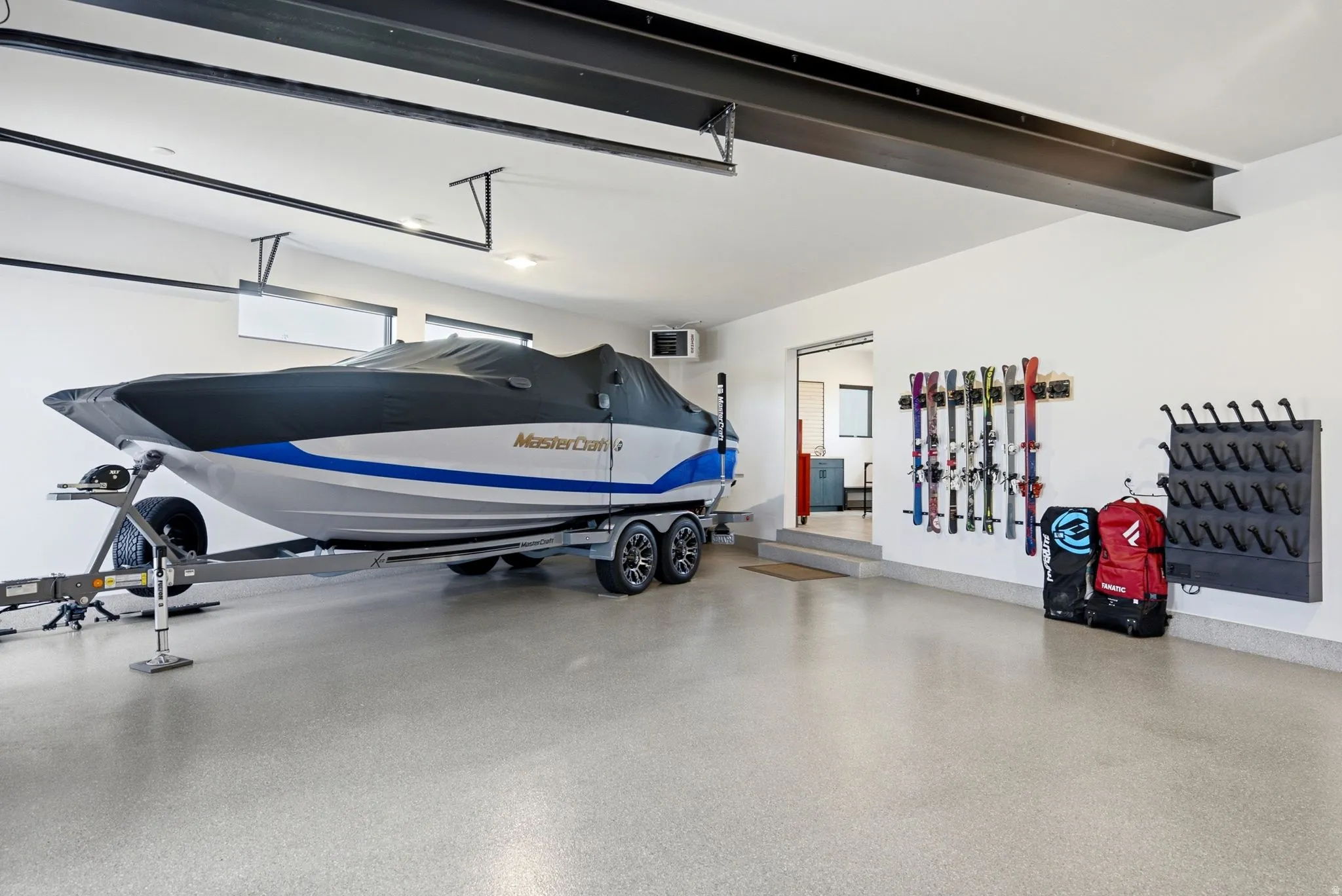 Spacious garage featuring a durable epoxy floor coating, exposed structural beams, and integrated wall-mounted storage racks