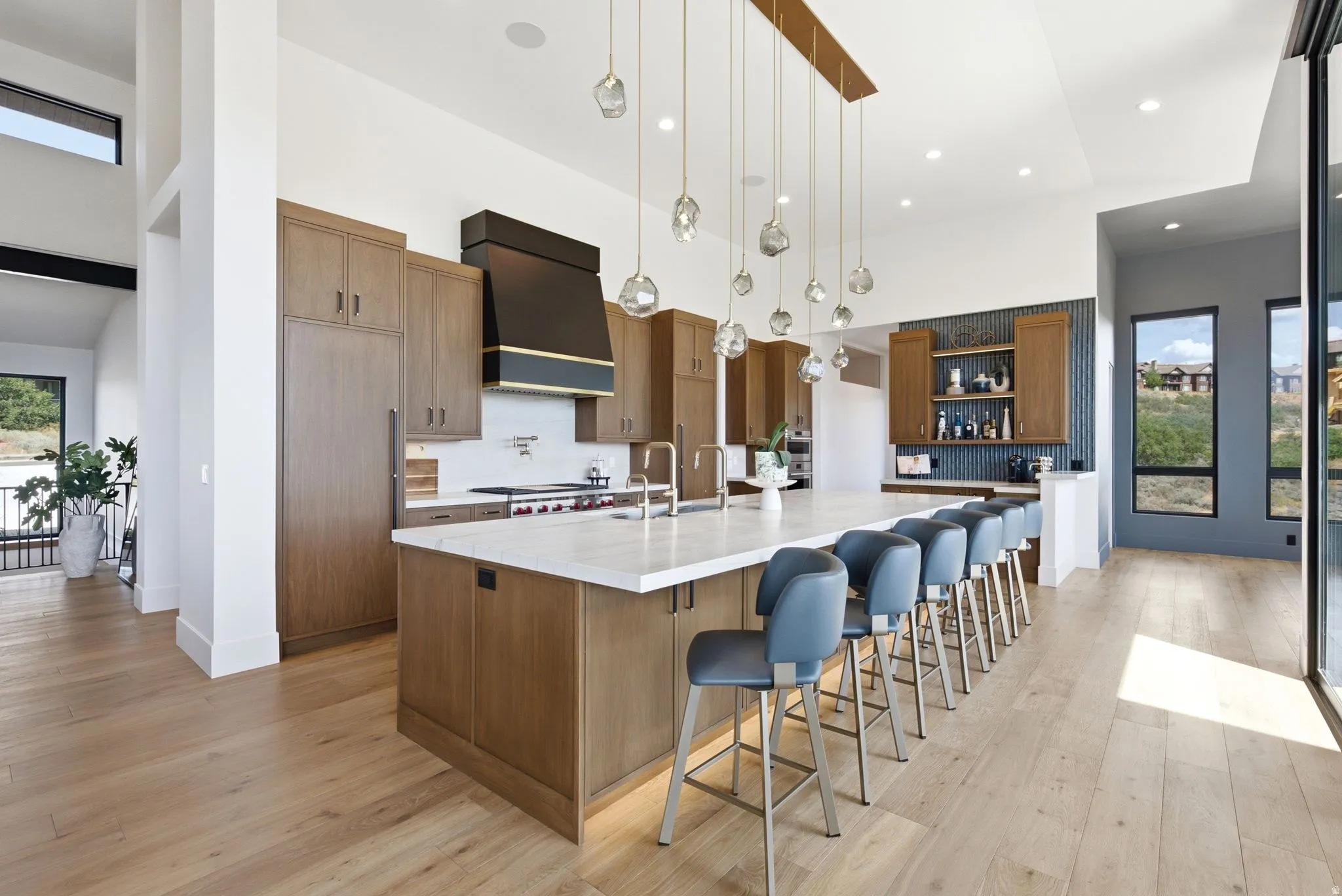 Spacious kitchen featuring an expansive central island with counter seating, integrated appliances, wood-finish cabinetry, and a built-in wet bar
