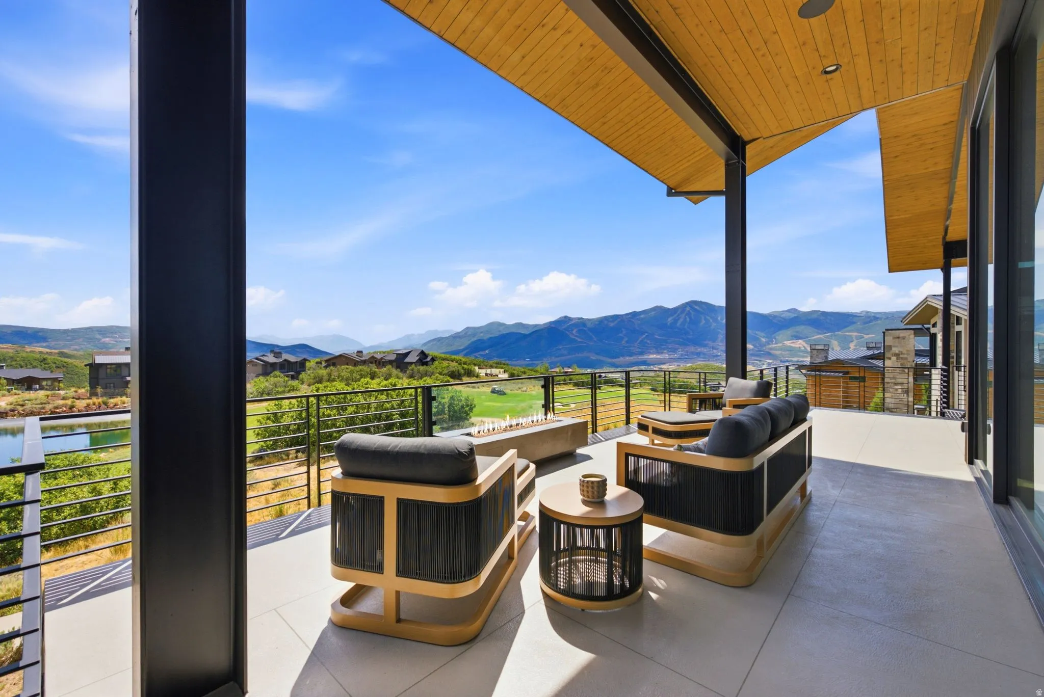 Expansive outdoor terrace featuring a wood-finish ceiling, mountain scenery, and glass panel railing
