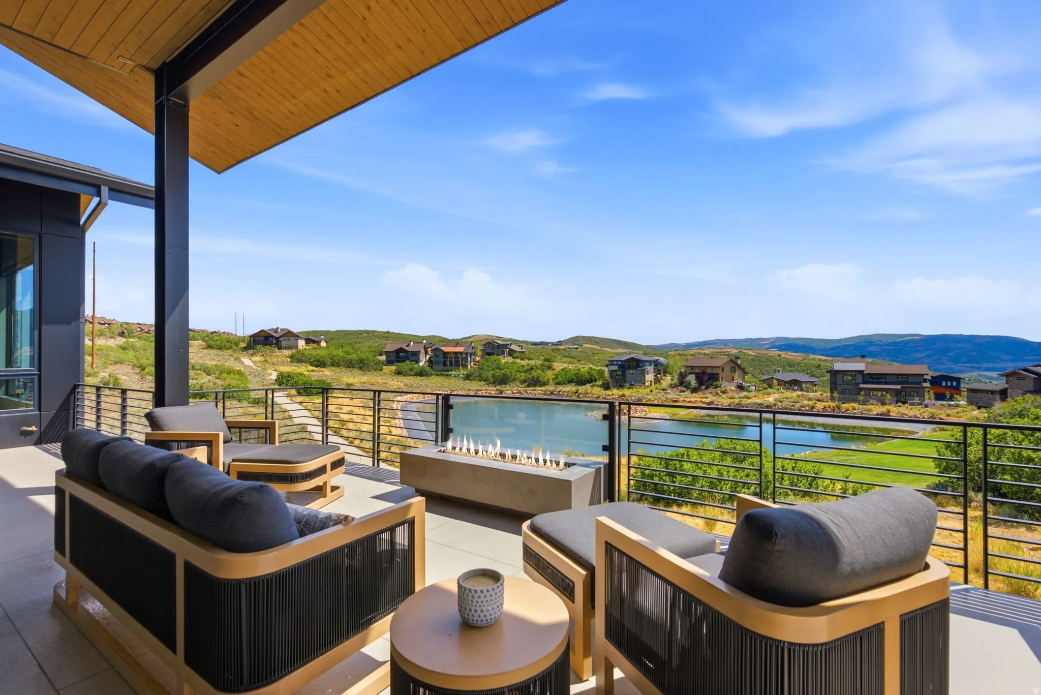 Expansive outdoor patio with a concrete fire pit, glass railing, and a sloped wood-paneled ceiling