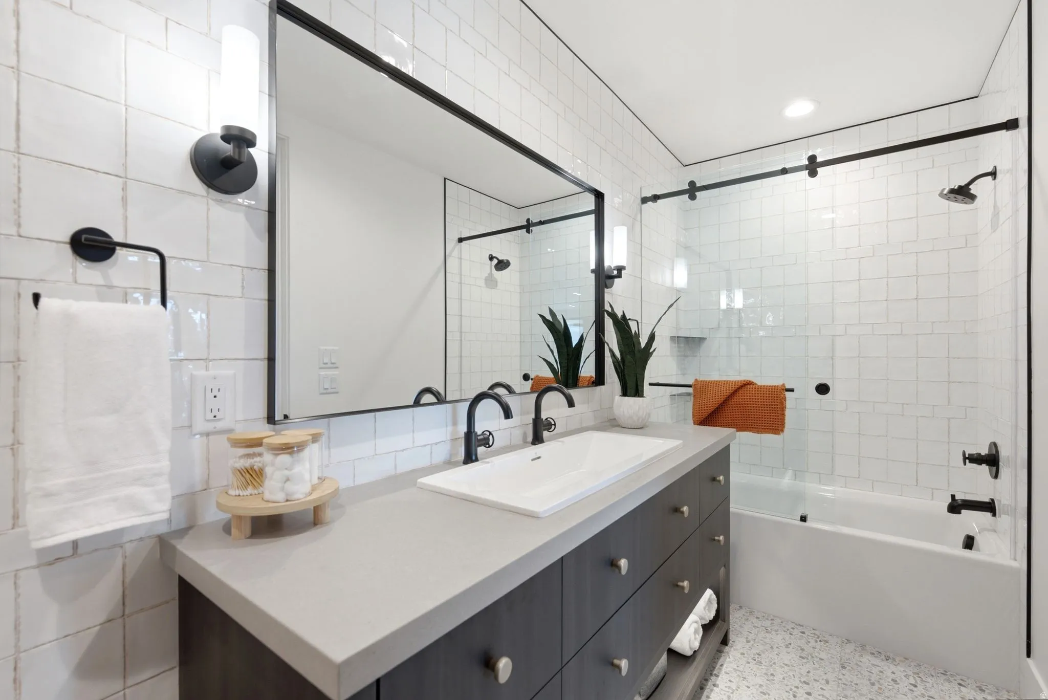 Bathroom featuring a dark wood-finish vanity with an integrated sink, light-toned countertop, and a large framed mirror