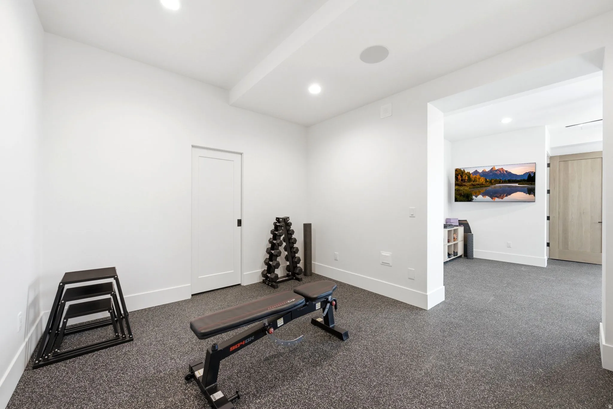 Rubberized flooring, recessed lighting, and a white interior door with black hardware