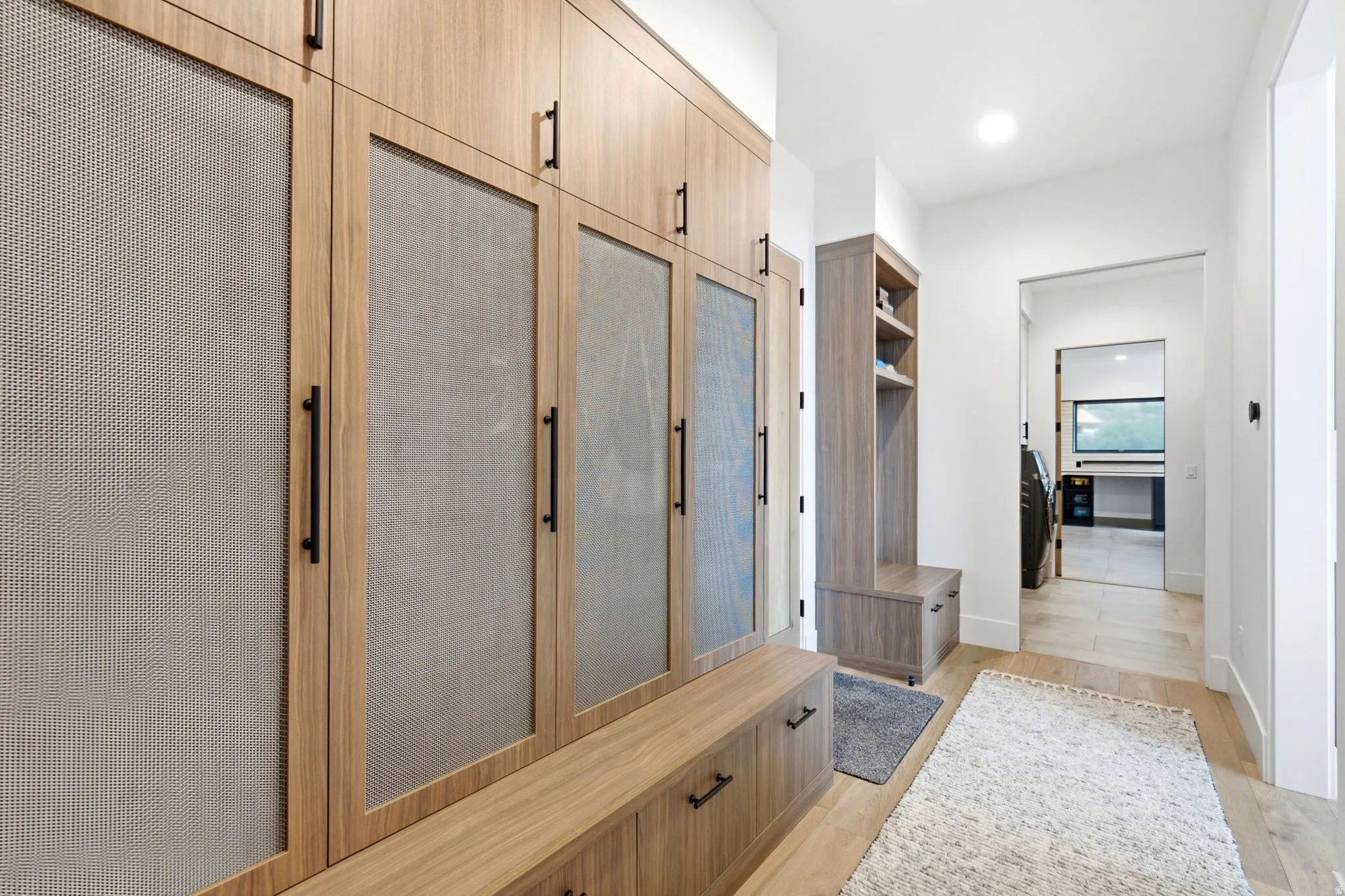 Custom built-in cabinetry with perforated panel inserts, integrated storage bench, and matte black hardware