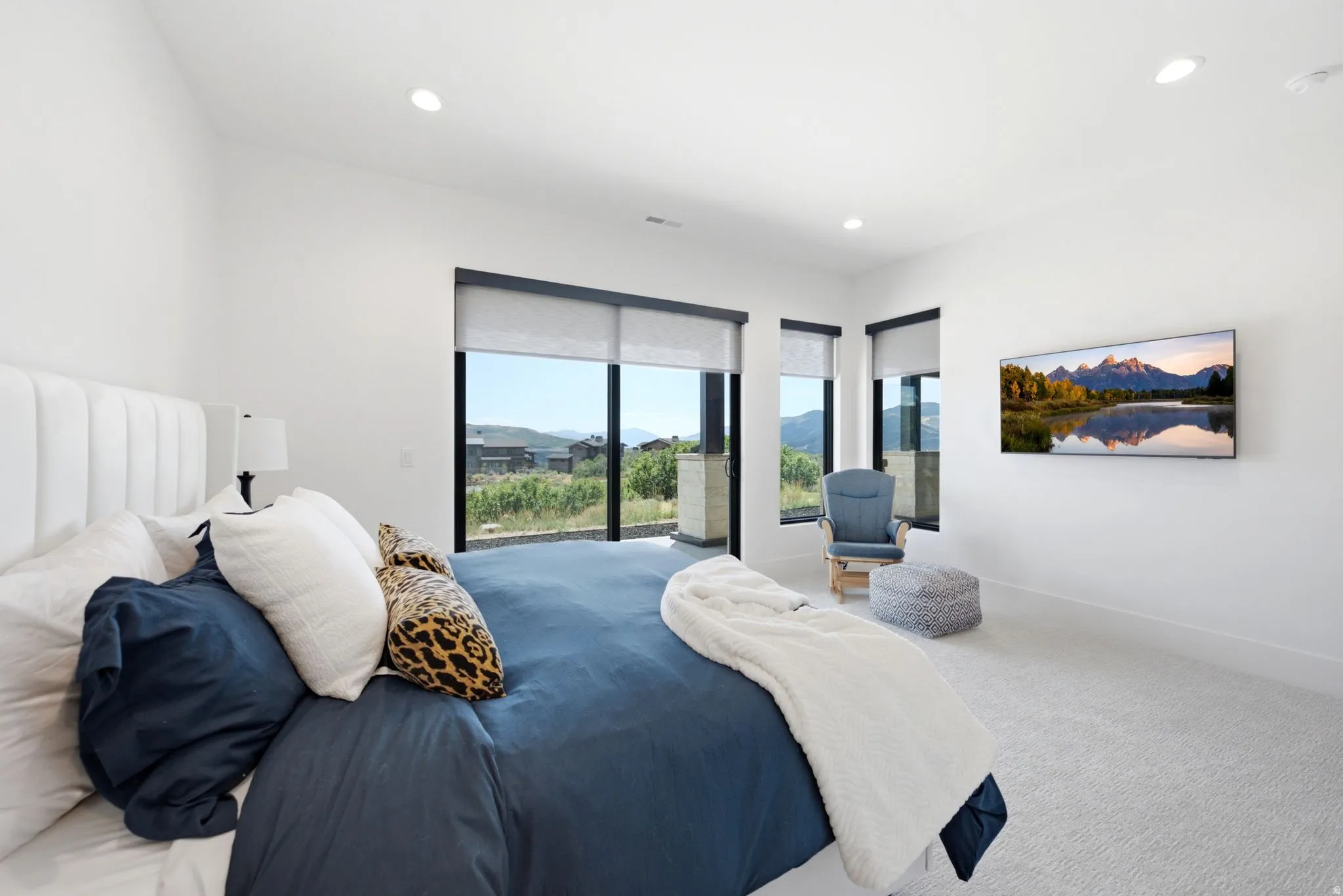 Recessed lighting, large format windows, sliding glass door, white walls, and light-colored carpeting