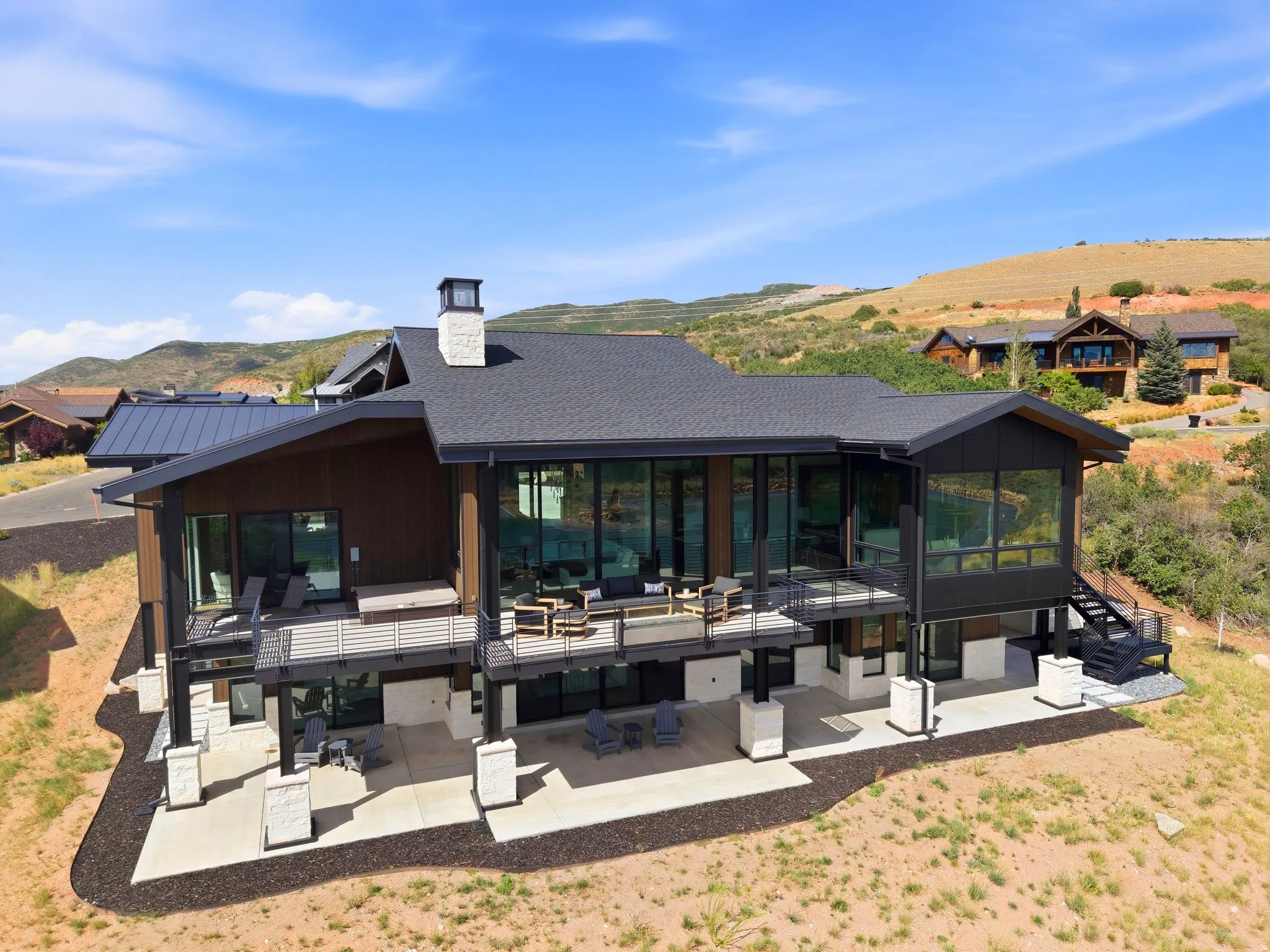 Multi-level dwelling with expansive glass panels, a stone chimney, and multiple balconies