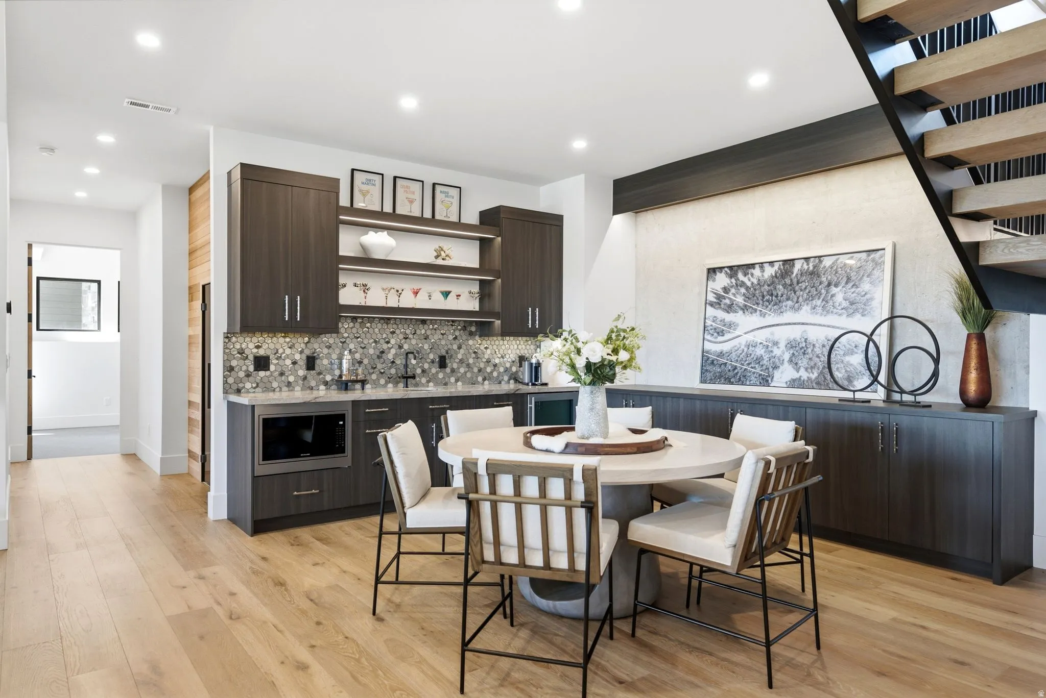 Hardwood flooring, built-in cabinetry, tiled backsplash, open shelving, and an open-tread staircase