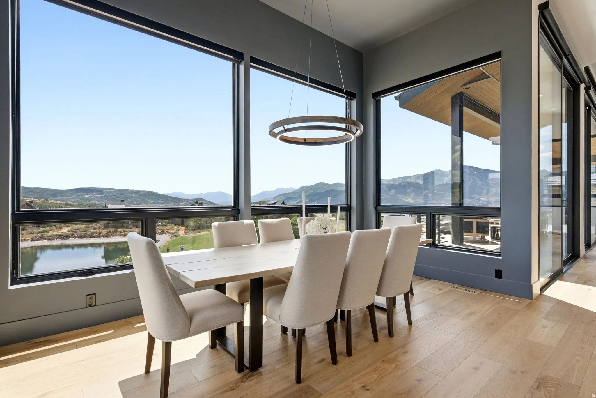 Floor-to-ceiling windows, wood-finish flooring, recessed lighting, and a contemporary chandelier