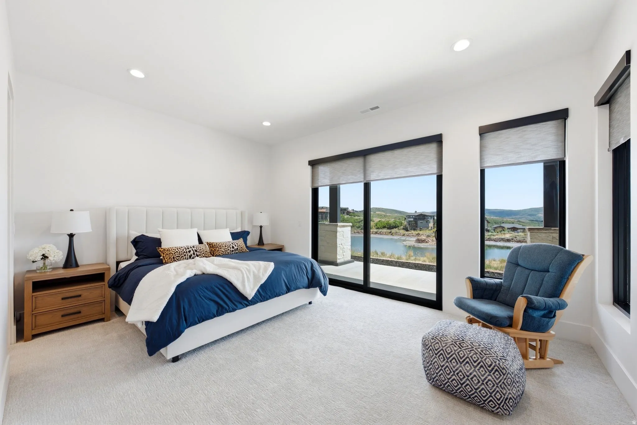 Recessed lighting, large format windows, sliding glass door, white walls, and light-colored carpeting