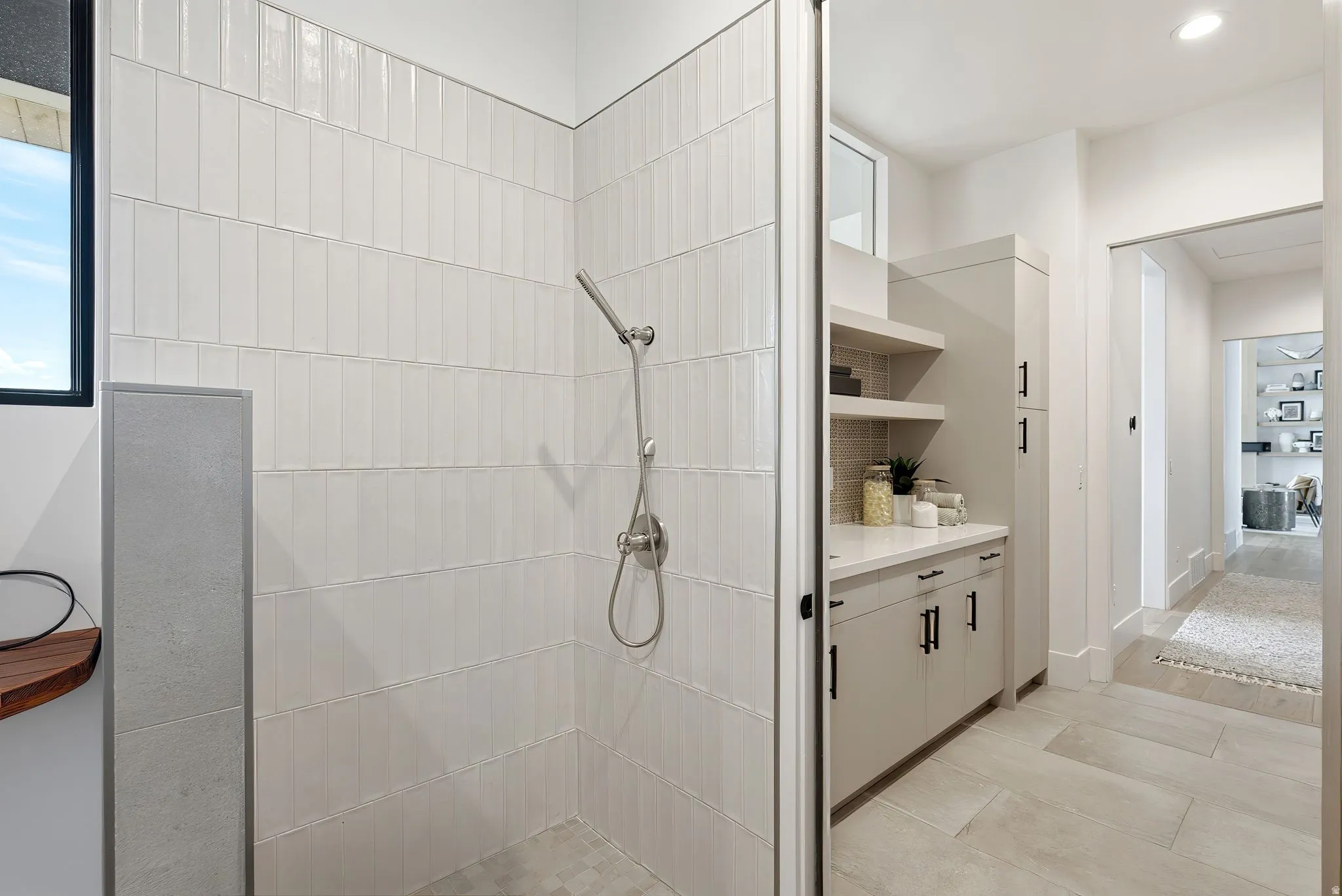 Walk-in shower with vertical tile work, integrated handheld shower fixture, and a built-in recessed window
