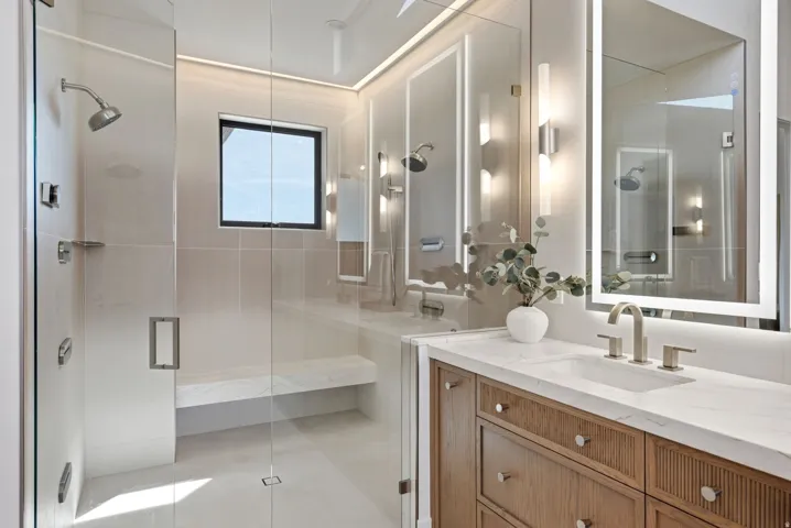 Glass-enclosed shower with a built-in bench, square window, and rainfall showerhead