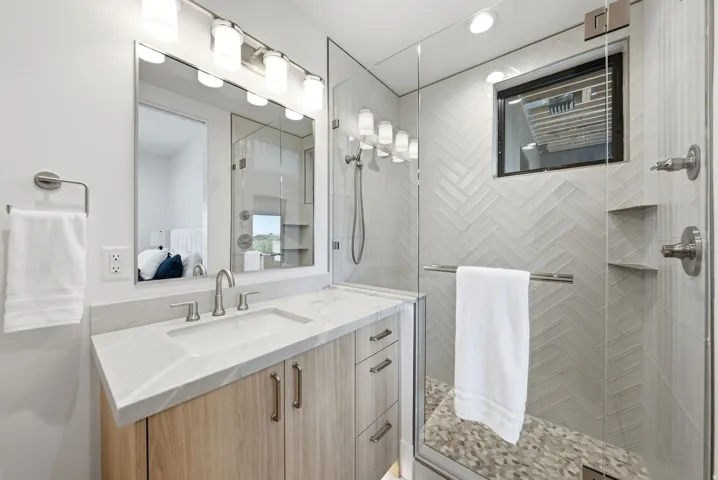 Spacious shower with glass enclosure and herringbone tile