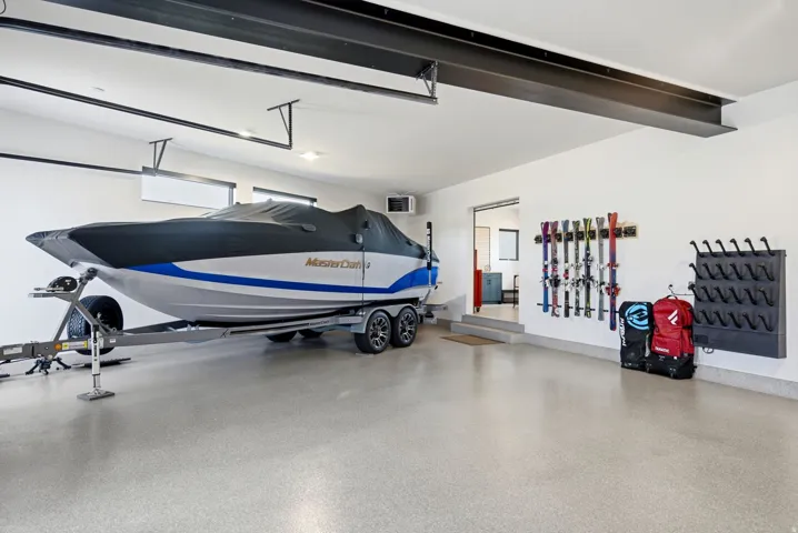 Spacious garage featuring a durable epoxy floor coating, exposed structural beams, and integrated wall-mounted storage racks