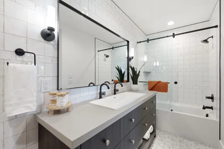 Bathroom featuring a dark wood-finish vanity with an integrated sink, light-toned countertop, and a large framed mirror
