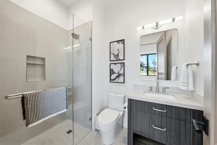 Glass-enclosed shower with a recessed niche, rainfall showerhead, and tiled flooring