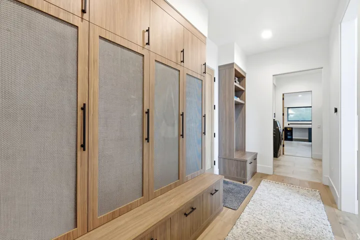 Custom built-in cabinetry with perforated panel inserts, integrated storage bench, and matte black hardware