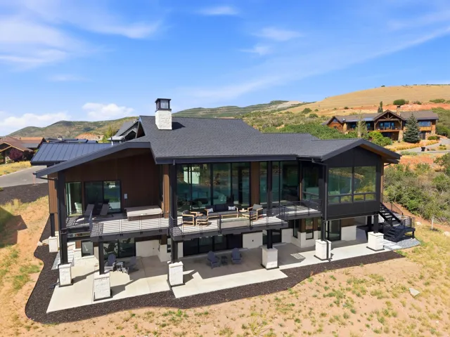 Multi-level dwelling with expansive glass panels, a stone chimney, and multiple balconies