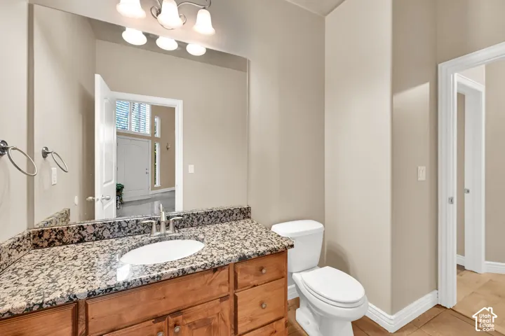 Vanity with a granite countertop, under mount sink, and wood cabinetry