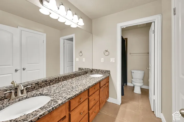 Dual vanity with granite countertop, undermount sinks, and wood cabinetry