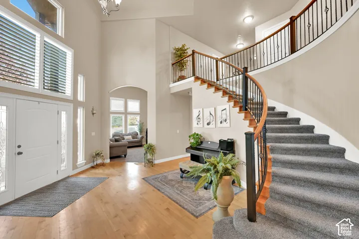 Two-story foyer with a grand curved staircase, wood flooring, and a double-entry door with sidelights
