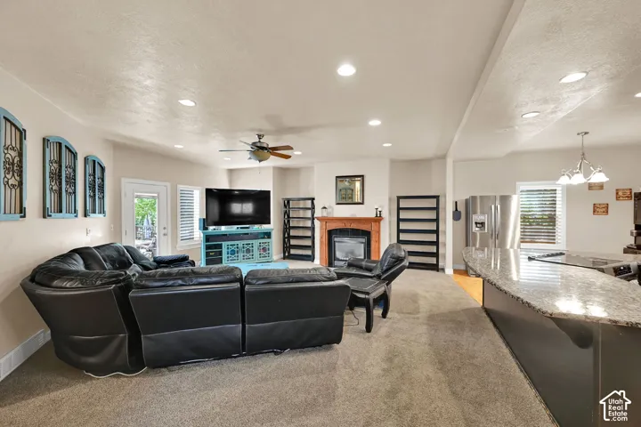 Recessed lighting, wood flooring, ceiling fan, fireplace with wood mantel, and a kitchen island with granite countertop