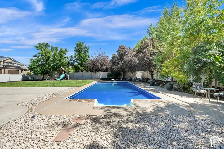 Rectangular in-ground pool with concrete surround and pebble landscaping