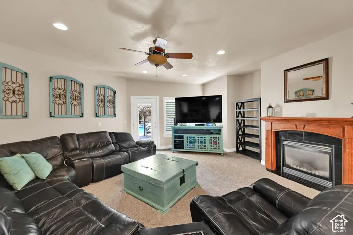 Spacious living area featuring a fireplace with a wood  mantle and tile surround, recessed lighting, and a ceiling fan