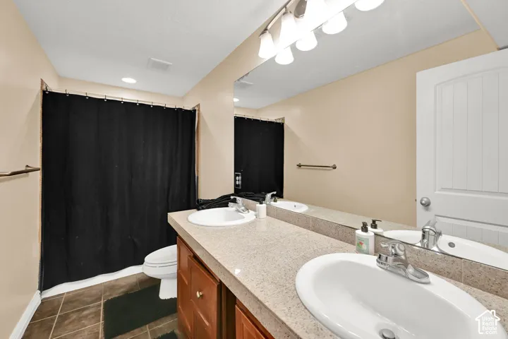 Dual vanity with integrated sinks, wood cabinetry, and a full-width mirror