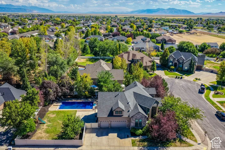 Residential property featuring a swimming pool, mature trees, a paved driveway, and a 4-car garage