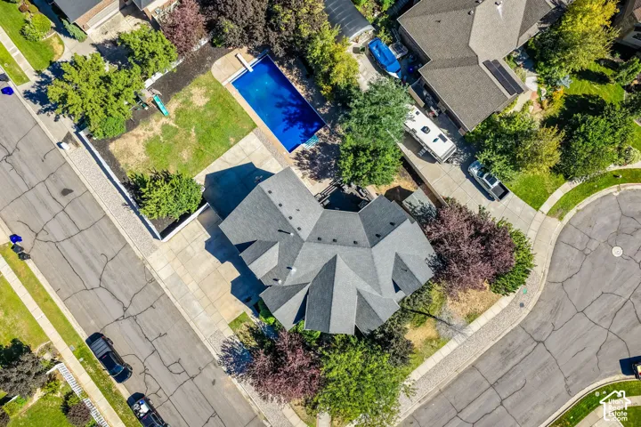 Geometric roofline, expansive concrete driveway, private backyard swimming pool, established landscaping, and corner lot position