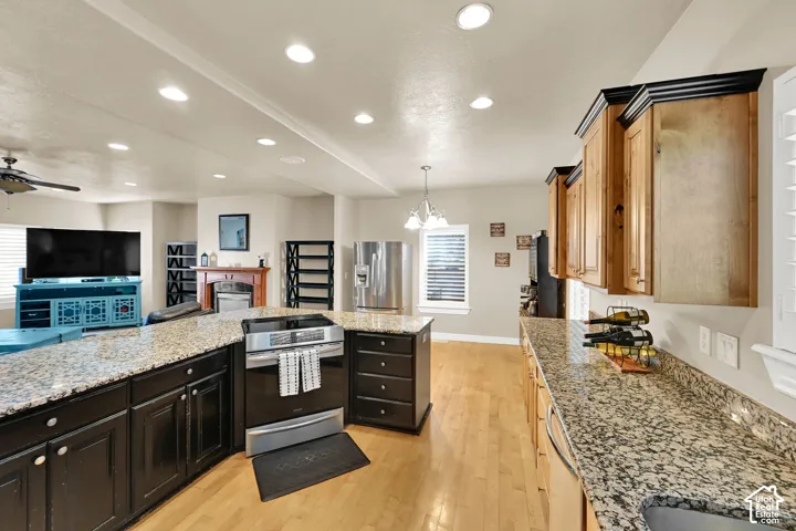 Open-concept kitchen featuring extensive granite countertops, wood flooring, recessed lighting, and induction/convention range