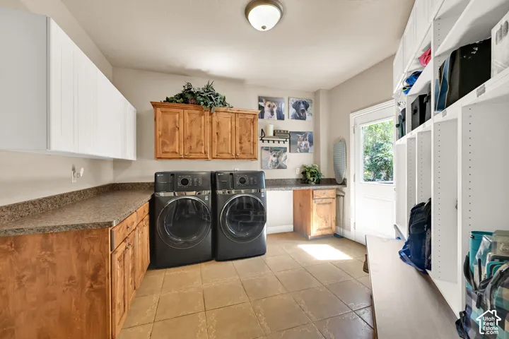 Utility room featuring tile flooring, built-in storage cubbies, a built-in bench, wood-finish cabinetry, and solid surface countertops