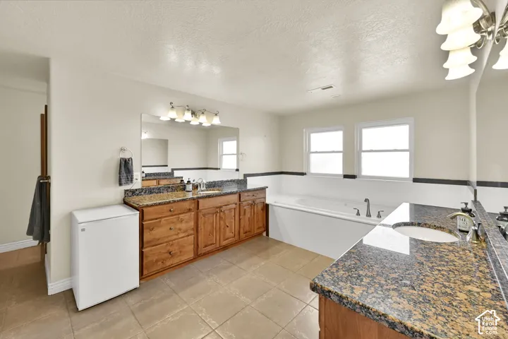 Dual vanity with granite countertops, wood cabinetry, built-in soaking tub,  tile flooring and separate shower