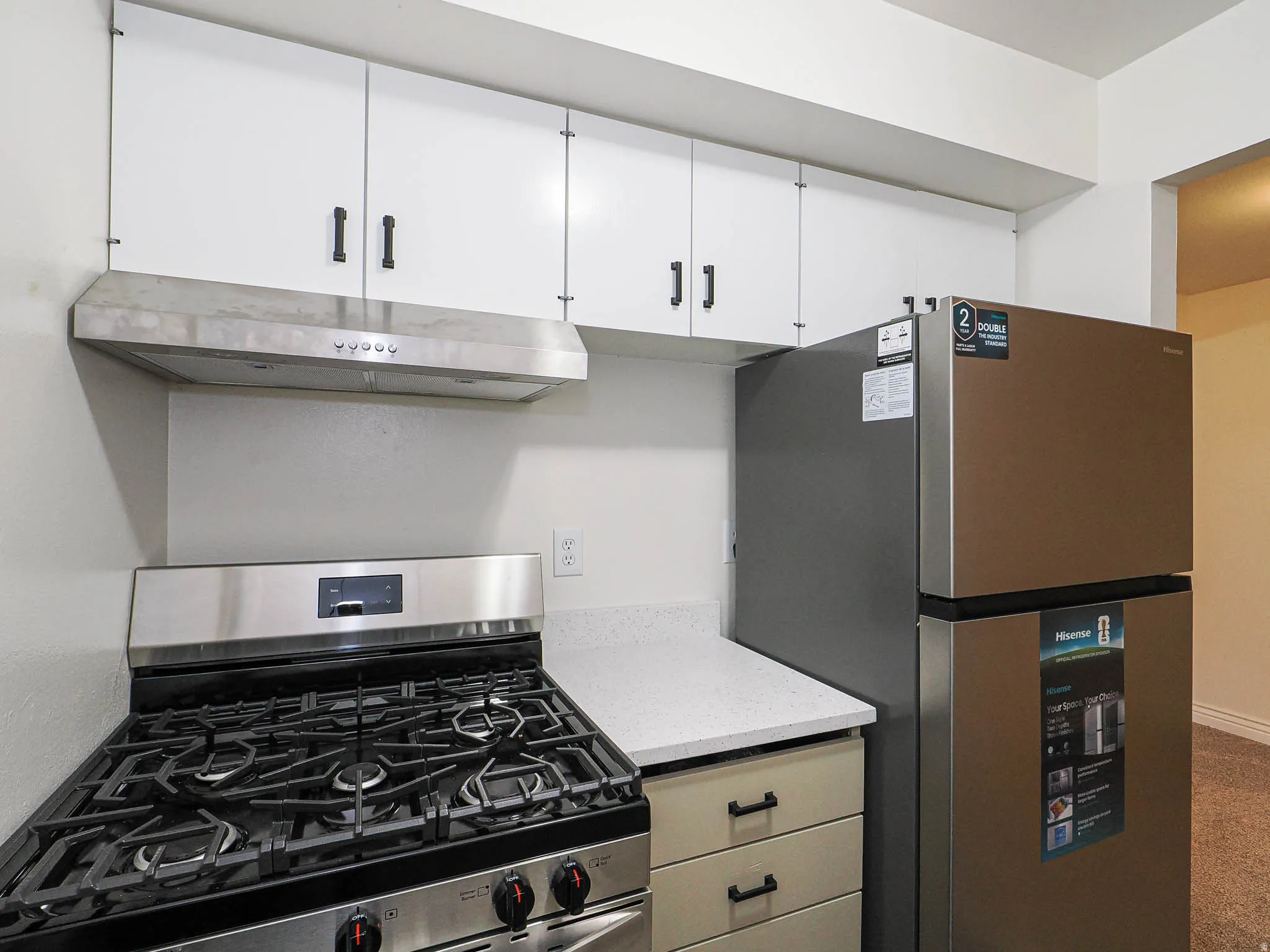 White upper cabinetry, stainless steel range hood, and a gas range