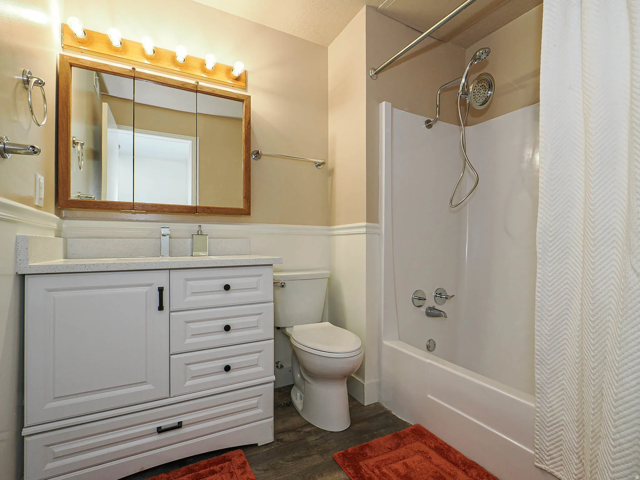 Vanity with a light-toned countertop, wood-framed medicine cabinet, and white panel-front cabinetry