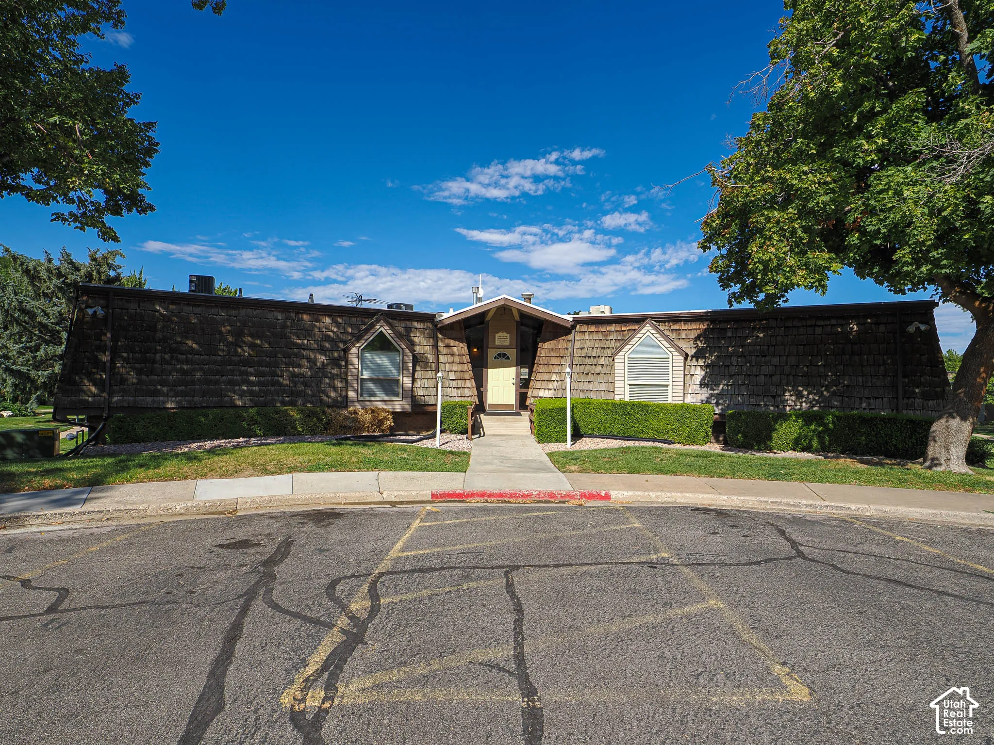 Wood shingle exterior with decorative arched windows and mature landscaping