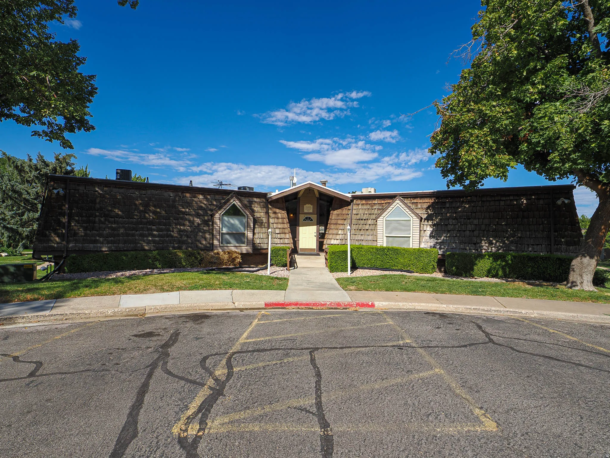 Wood shingle exterior with decorative arched windows and mature landscaping