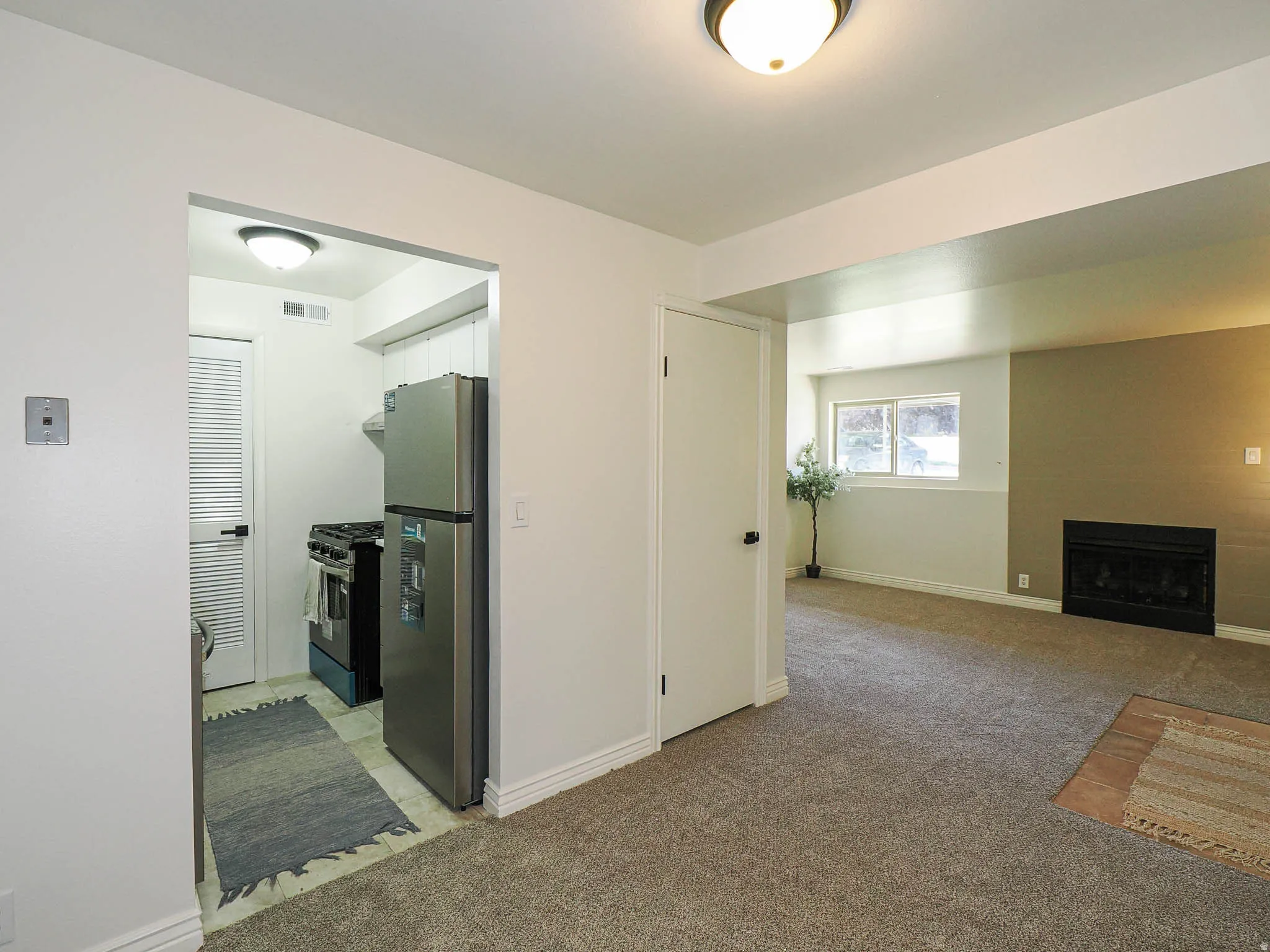Recessed kitchen featuring stainless steel refrigerator, black range, and tile flooring