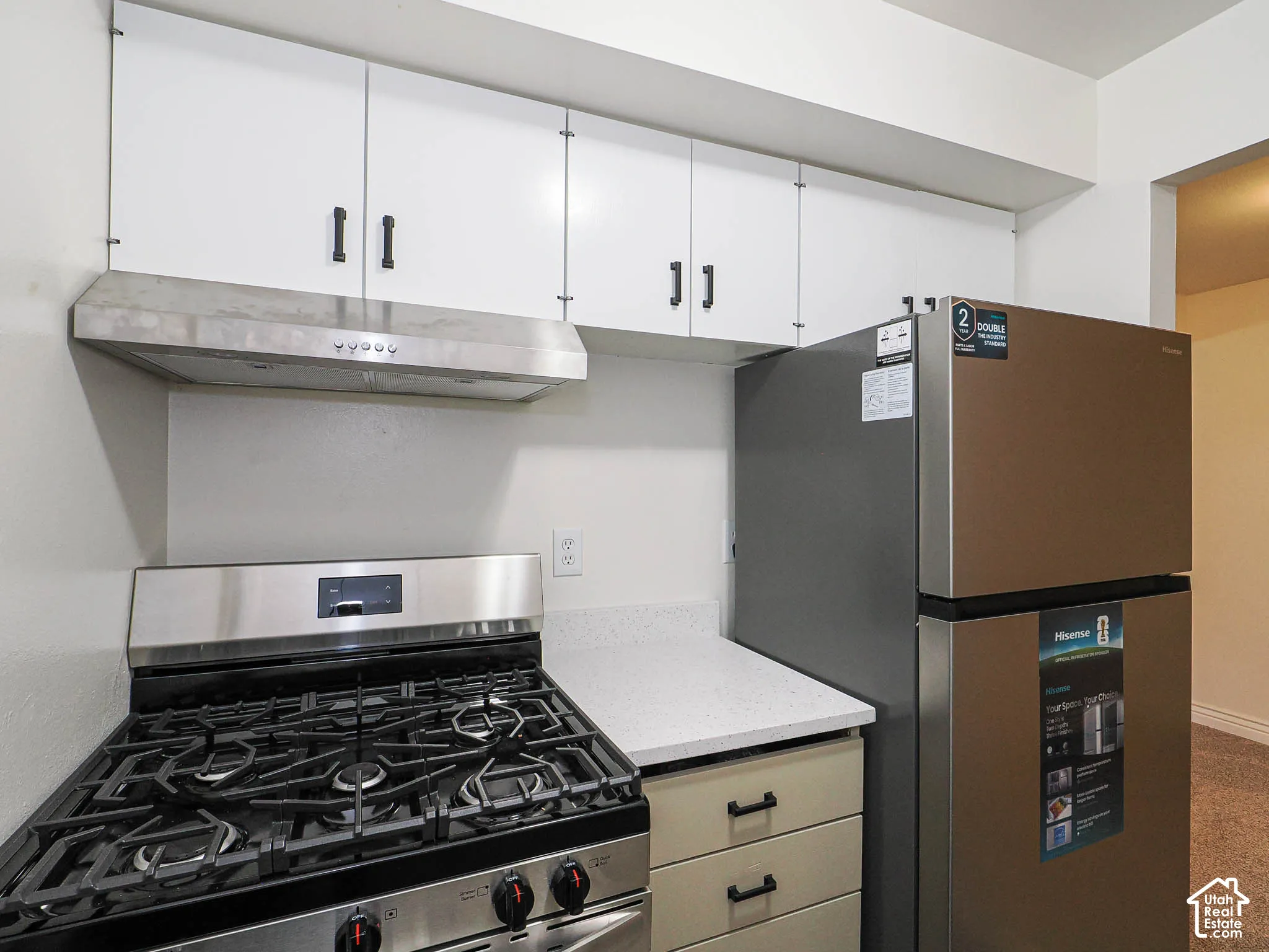 White upper cabinetry, stainless steel range hood, and a gas range